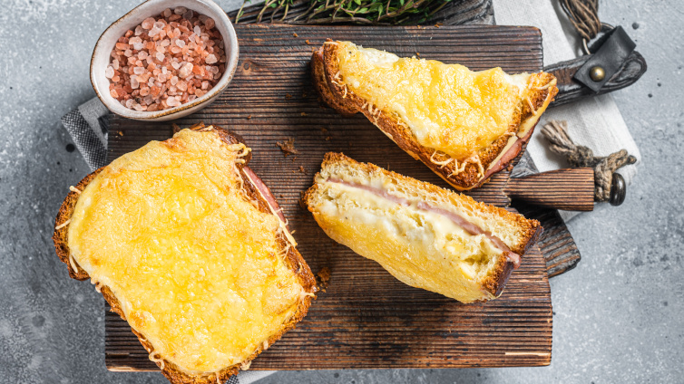 Überbackener Toast liegt auf einem Holzbrett neben einer Schüssel mit Steinsalz.