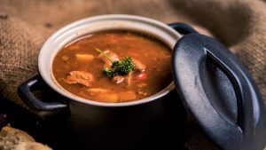 Gulaschsuppe in einem schwarzen Töpfchen mit Deckel serviert