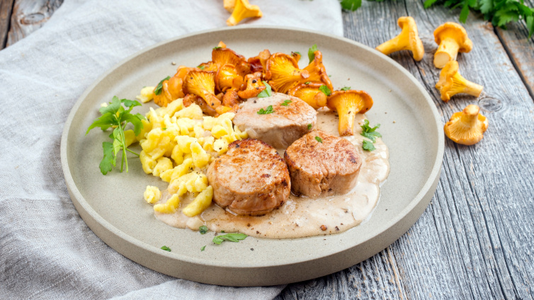 Schweinemedaillons mit Pfifferlingen und Spätzlen auf einem Teller.