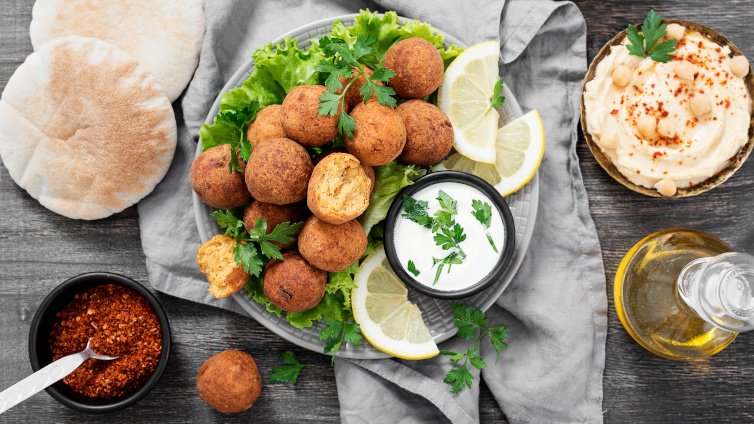 Falafel-Bällchen auf einem Teller mit Dip und Fladenbrot.