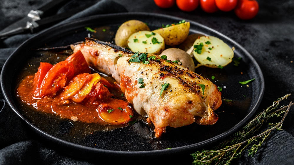 Seeteufel auf einem Teller mit Tomaten und Kartoffeln.