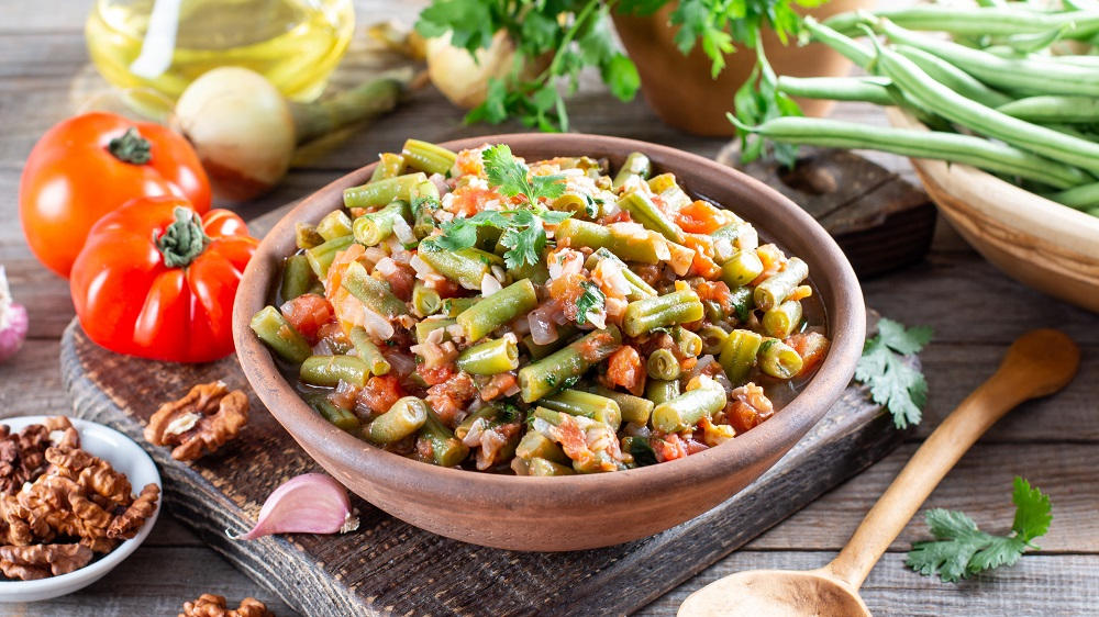 Grüne Bohnen mit Tomaten und weiteren Zutaten in einer Schüssel.