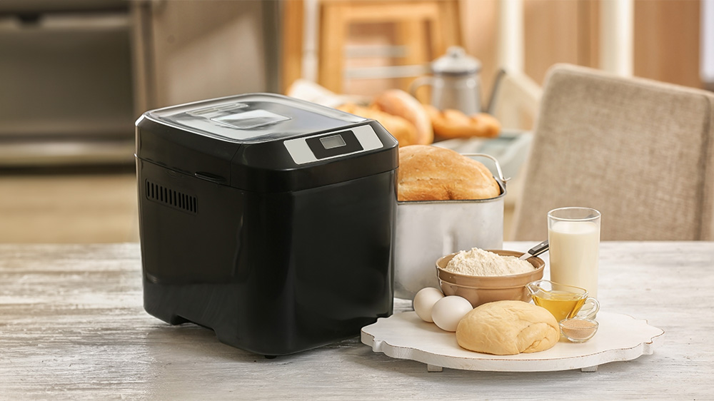 Brotbackautomat mit gebackenem Brot und Zutaten steht in der Küche