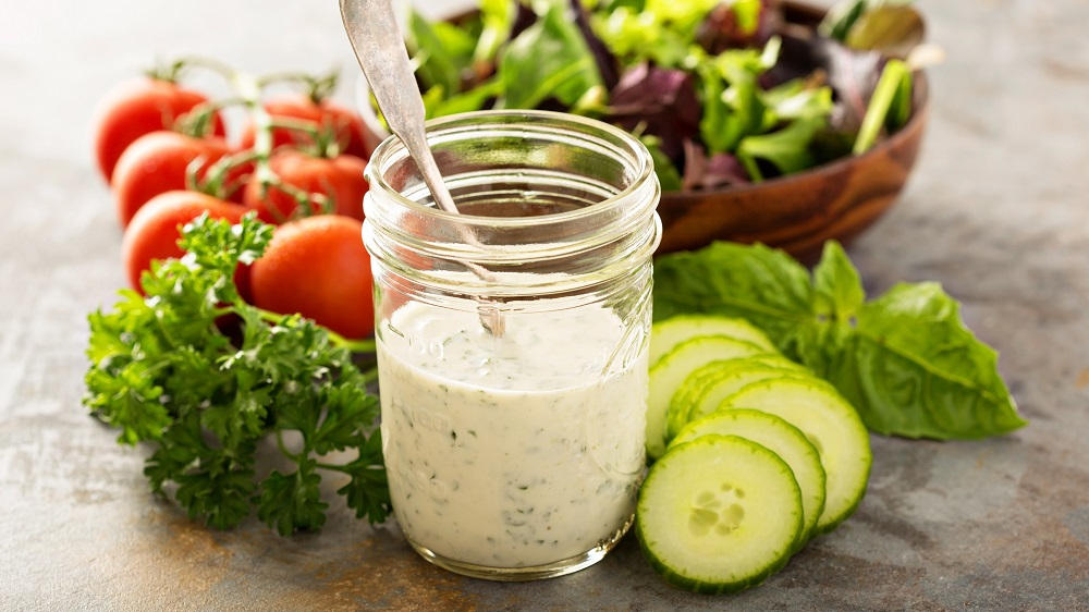 Joghurt Dressing mit Salatzutaten in einem Gefäß.