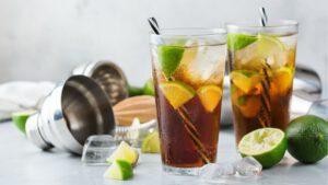 Zwei Long Island Iced Teas in Gläsern mit Eis, Limetten und Strohhalm garniert.