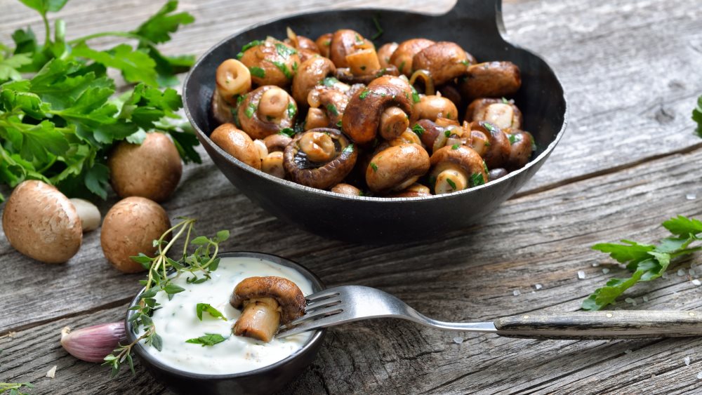 Gebratene Champignons in einer Pfanne mit Soße.